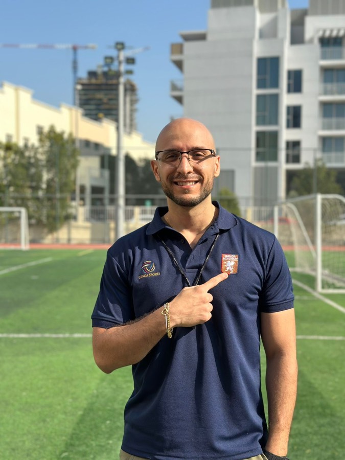 Genoa Academy coach pointing at the badge